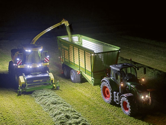 krone feldhäcksler bei nacht neben traktor beläd kipper