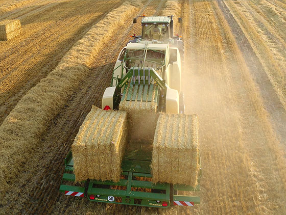 traktor mit krone großpackenpresse fährt über gemähtes feld