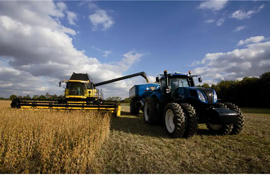 intellisteer blauer new holland traktor mit anhänger und gelber mähdrescher fahren geführt nebeneinander