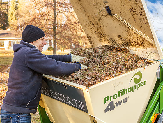 mann mit schwarzer mütze und blauem pullover leert amazone kommunaltechnik behälter herbst