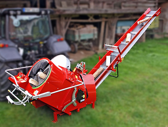 rote unterreiner trommelsäge mit holzscheiten hinter traktor